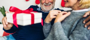 Romantik tatlı yaşlı çift sevgililer gününü birlikte kutlarken eğleniyor ve gülümsüyor. Son sınıf öğrencisi, sevgililer gününde evde karısına sürpriz hediye paketi veriyor.