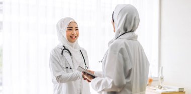 Steteskoplu, üniformalı iki profesyonel tıbbi Müslüman kadın doktor hastanede görüşmeler ve danışmanlık konuşmaları yapıyor.