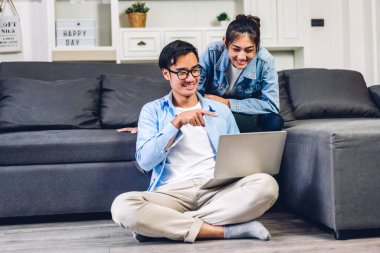 Genç Asyalı çift dizüstü bilgisayarlarını kullanarak rahatlıyor. İnternetteki video konferansında sohbet ediyorlar. Evde yaratıcı iş çifti planlama ve beyin fırtınası yapıyorlar.