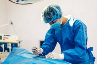 Profesyonel anestezi uzmanı doktor tıp ekibi ve asistanı modern hastane acil servisinde cerrahi ekipmanla jinekolojik ameliyata hazırlanıyor.