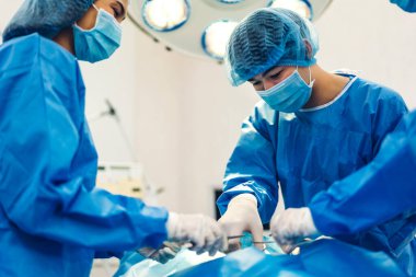 Profesyonel anestezi uzmanı doktor tıp ekibi ve asistanı modern hastane acil servisinde cerrahi ekipmanla jinekolojik ameliyata hazırlanıyor.