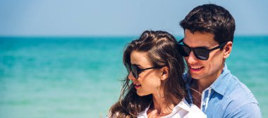 Romantik bir tatil aşkı genç mutlu çift, tropik plajlara yazı eklemek için denizde kumda durup eğleniyorlar ve birlikte rahatlıyorlar.