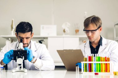 Profesyonel iki bilim adamı test tüpünde sıvı analiz ederken ve karıştırırken kimyasal bir deney yapıyor. Genç bilim adamı laboratuvarda cam üzerine kimyasal örnekler bırakıyor.