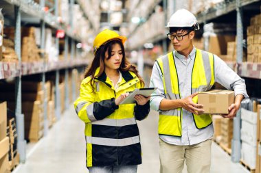 Miğfer mühendisi Asyalı iki mühendis, malzeme ve malzemelerin depo geçmişine sahip raflarda kontrol edilmesi için tablet bilgisayardan talimat verdi. Lojistik ve ticari ihracat