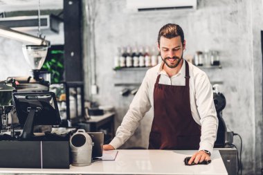 Yakışıklı sakallı baristanın portresi. Küçük işletme sahibi bir kafede tezgahın arkasında çalışıyor.