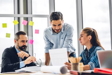 Profesyonel iş toplantıları ve yeni başlangıç projesiyle strateji tartışmaları. Yaratıcı iş adamları modern çalışma ortamında belge raporlarıyla plan yapıyor ve beyin fırtınası yapıyorlar. Takım çalışması kavramı.