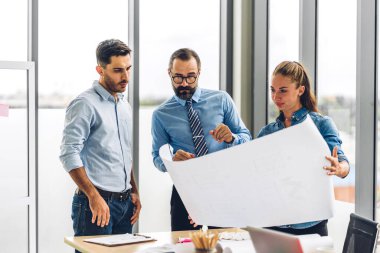 Profesyonel iş toplantıları ve yeni başlangıç projesiyle strateji tartışmaları. Yaratıcı iş adamları modern çalışma ortamında belge raporlarıyla plan yapıyor ve beyin fırtınası yapıyorlar. Takım çalışması kavramı.