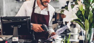 Yakışıklı sakallı baristanın portresi. Küçük işletme sahibi. Kafenin arkasında bilgisayarla çalışıyor.