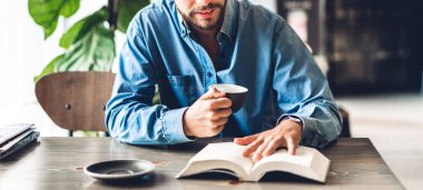 Yakışıklı hippi kahve içiyor, gazete okuyor, kitap okuyor ve kafe ve restoranda sandalye üzerinde otururken magazin dergilerine bakıyor.