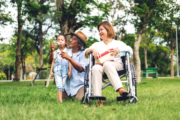 Mutlu Asyalı büyükbaba ve büyükannesinin portresi ve Asyalı küçük tatlı kız yaz parkında rahatlayın. Gülen büyükannesi ve büyükbabası birlikte gülümseyen genç kız. Aile ve beraberlik.