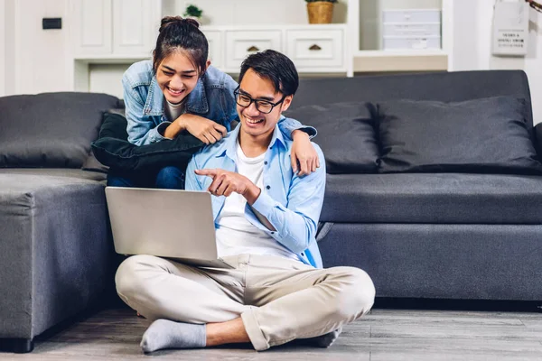 Genç Asyalı çift dizüstü bilgisayarlarını kullanarak rahatlıyor. İnternetteki video konferansında sohbet ediyorlar. Evde yaratıcı iş çifti planlama ve beyin fırtınası yapıyorlar.