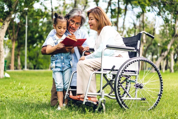 Mutlu Asyalı büyükbaba ve büyükannesinin portresi ve Asyalı küçük tatlı kız yaz parkında rahatlayın. Gülen büyükannesi ve büyükbabası birlikte gülümseyen genç kız. Aile ve beraberlik.