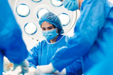 Profesyonel anestezi uzmanı doktor tıp ekibi ve asistanı modern hastane acil servisinde cerrahi ekipmanla jinekolojik ameliyata hazırlanıyor.