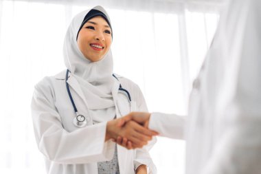 İki Asyalı Müslüman ortağın birlikte gülümsemesi doktor kadın tokalaşması. Profesyonel Müslüman doktor buluşması ve hastanede el sıkışması. Sağlık ve tıp.