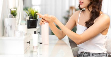 Güzel, güzel Asyalı bir kadının gülümsemesi taze, sağlıklı, beyaz bir tenin aynaya bakışıyla. Asyalı bir kızın vücut losyonunu tutması ve evde nemlendirici krem sürmesi. Spa ve güzellik konsepti.