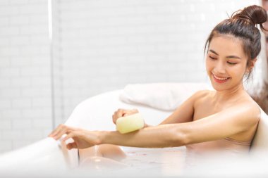 Mutlu, güzel Asyalı güzel bir kadının portresi temiz, sağlıklı, beyaz bir cilt spa tedavisiyle rahatlamanın ve banyo yaparken banyo köpüklü spa ile banyo yapmanın keyfini çıkar.