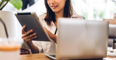 Gülümseyen mutlu Asyalı bir kadının portresi dizüstü bilgisayar teknolojisini kullanarak rahatlıyor. Genç hippi Asyalı kız serbest çalışıyor ve kafeteryada yeni fikirler üretiyor.