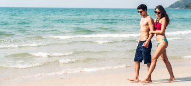 Romantik aşıklar genç mutlu çift deniz kenarında el ele yürüyor ve tropik plajlara metin eklemek için fotokopi çekiliyor. Yaz tatilleri ve seyahatler
