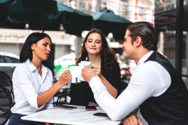 Bir grup neşeli genç arkadaş buluşmayı tartışıyor ve birlikte kahve içerek eğleniyorlar. Kafe masasında ve restoranda karışık ırkçı insanlar oturuyor.