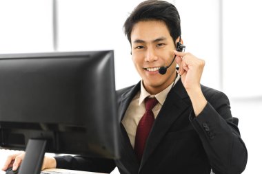 Mutlu çağrı merkezi gülümseyen işadamı müşteri desteği danışma hizmetleri ajanı çağrı merkezindeki kablosuz mikrofon ve bilgisayarla çalışıyor.