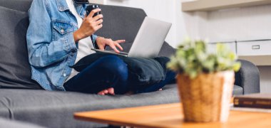 Genç gülümseyen Asyalı kadın dizüstü bilgisayar kullanıyor ve evdeki iş arkadaşlarıyla çevrimiçi toplantı yapıyor. Genç yaratıcı kız, ev konseptinden iş ekibiyle video konuşması yapıyor.