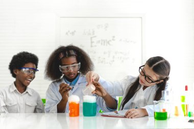 Okuldaki deney laboratuarında test tüpünde sıvı karıştırıp analiz ederken araştırma yapmayı ve kimyasal deney yapmayı öğrenen bir grup küçük tatlı öğrenci. Eğitim.