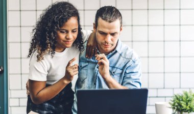 Dizüstü bilgisayarla çalışan mutlu bir çift. Yaratıcı iş çifti. Evdeki oturma odasında beyin fırtınası ve planlama.