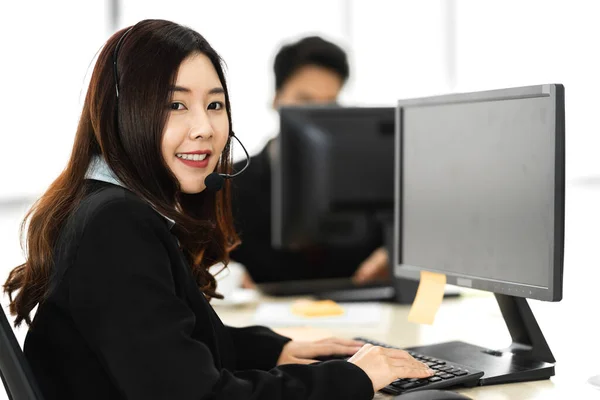 美丽而快乐的呼叫中心微笑着亚洲商人女性运营商客户支持电话服务在呼叫中心与耳机和计算机一起工作 — 图库照片