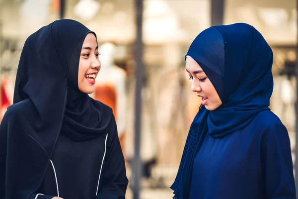 Portrait of happy arabic two friend muslim woman with hijab dress smiling and talking together at store