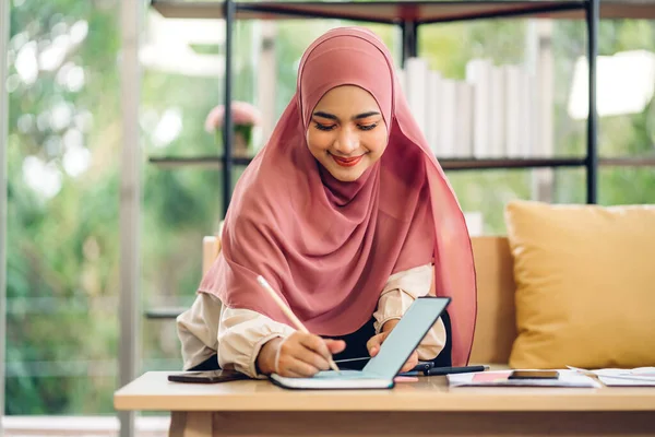 若い笑顔の美しいイスラム教徒の女性は 自宅でノートパソコンの作業やビデオ会議会議を使用してリラックスしています — ストック写真