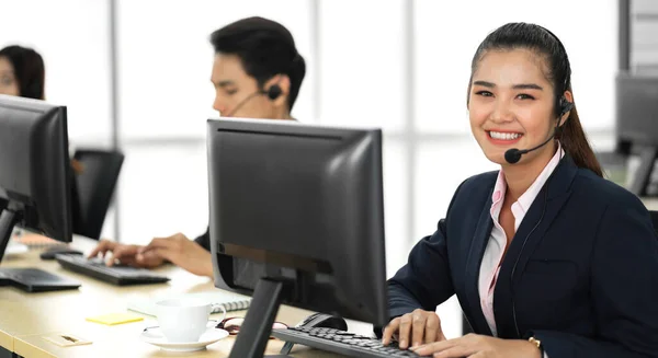 在呼叫中心办公室的台式机上 一群快乐的亚洲人微笑着呼叫中心的经营者帮助支持团队电话服务 — 图库照片