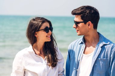 Romantik aşıklar. Genç mutlu çift, tropikal sahillerde sarılıp kumsalda dinleniyorlar. Yaz tatilleri.