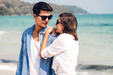 Romantik aşıklar. Genç mutlu çift, tropikal sahillerde sarılıp kumsalda dinleniyorlar. Yaz tatilleri.