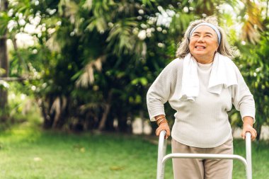 Mutlu, yaşlı, gülümseyen ve hisseden Asyalı bir kadının portresi. Parkta güneşli bir sabahta temiz hava ve egzersiz. Emeklilik ve sağlık sigortası kavramı.