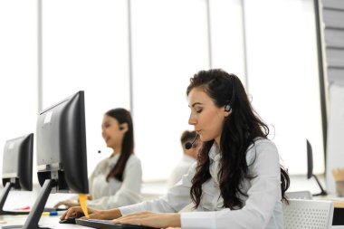 Mutlu çağrı merkezi gülümseme operatörü müşteri destek ekibi telefon hizmeti ajansı çağrı merkezindeki masaüstü bilgisayarında çalışıyor ve kulaklıkla konuşuyor
