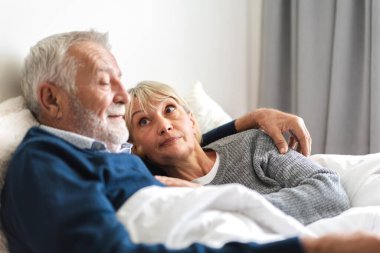 Üst düzey mutlu çift evde yatak odasında uzanıp sohbet ediyor. Emekliler konsepti.