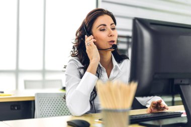 Güzel, mutlu çağrı merkezi gülümseyen iş kadını operatörü müşteri desteği danışma hizmetleri temsilcisi çağrı merkezindeki kablosuz mikrofon ve bilgisayarla çalışıyor.