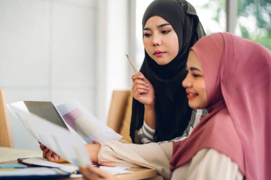 Genç, gülümseyen, mutlu, Asyalı Müslüman bir kadın dizüstü bilgisayarını kullanarak rahatlıyor ve evde video konferansı yapıyor. Ev konseptinden çalışma.