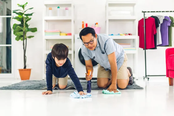 父教えアジアの子供小さな男の子使用消毒スプレーボトルクリーニングと洗濯床拭くほこりでラグで家を掃除しながら一緒に家 — ストック写真