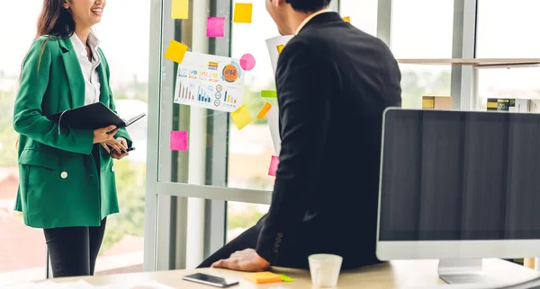 Casual creative happy two smile asian business people planning strategy analysis and brainstorm putting post it stickers note to share idea for startup project on glass board at modern office