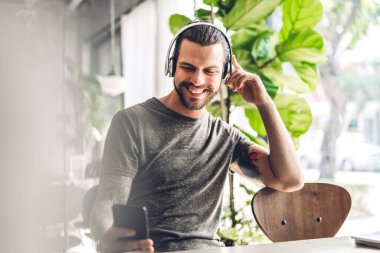 Yakışıklı hippi, dijital akıllı telefon kullanarak rahatlıyor ve kafeteryada ve restoranda ekran daktilo mesajlarına bakıyor, online ve sosyal medyada oyun oynuyor.