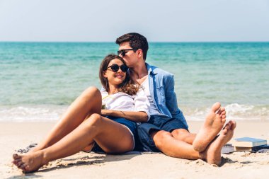 Romantik aşıklar. Genç mutlu çift, tropikal sahilde sarılıp kumsalda durup eğleniyor ve dinleniyorlar. 