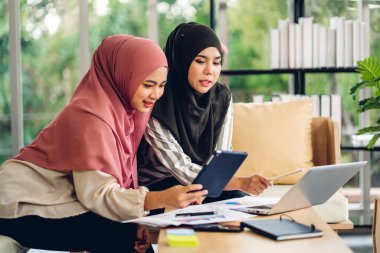 Genç, gülümseyen, mutlu, Asyalı Müslüman bir kadın dizüstü bilgisayarını kullanarak rahatlıyor ve evde video konferansı yapıyor. Ev konseptinden çalışma.
