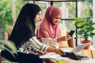 Genç, gülümseyen, mutlu, Asyalı Müslüman bir kadın dizüstü bilgisayarını kullanarak rahatlıyor ve evde video konferansı yapıyor. Ev konseptinden çalışma.