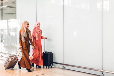 İki genç, güzel, Asyalı Müslüman kadın tesettüre girmiş, alışveriş yapıyor ve moda mağazasında sohbet ederken eğleniyor.