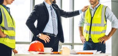 İnşaat sahasında planlar ve inşaat araçlarıyla çalışan miğferli ekip mühendisi ustabaşı.