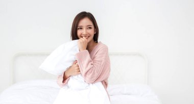 Gülümseyen, güzel Asyalı güzel bir kadın taze, sağlıklı, temiz, pembemsi giysiler içinde poz veriyor. Kız evde dinleniyor ve eğleniyor. Asya güzeli.