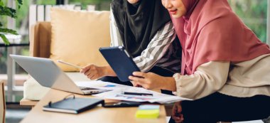 Genç, gülümseyen, mutlu, Asyalı Müslüman bir kadın dizüstü bilgisayarını kullanarak rahatlıyor ve evde video konferansı yapıyor. Ev konseptinden çalışma.