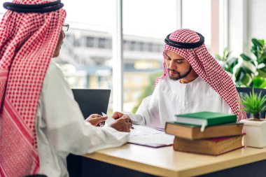 Üniversiteli Arap iş adamlarının dizüstü bilgisayar ve belge raporlarıyla çalışmalarının başarısı. Yaratıcı Arap iş adamları yeni bir başlangıç projesi projesiyle buluşup strateji analizi planlıyorlar.