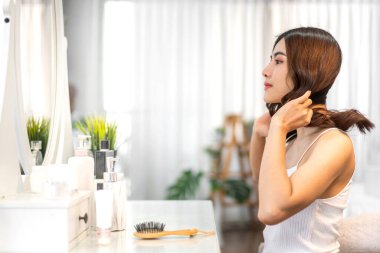 Gülümseyen, güzel, güzel Asyalı kadın güzellik bembeyaz giysiler içinde temiz, sağlıklı beyaz ten. Düşen ve eğlenen kız Home.Asia güzellik salonundaki aynaya bak.